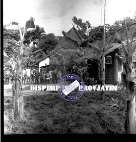 Anak-anak sedang berkumpul, sebagian bertelanjang dada berada didepan sebuah rumah dengan atap ru...