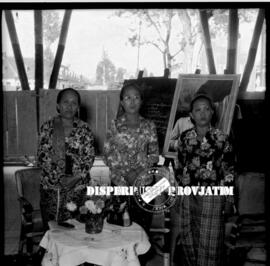 Tiga orang perempuan sedang berdiri dalam sebuah acara pertemuan yang merupakan gabungan organisa...