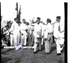 Seorang pejabat / tokoh sedang berjalan dengan melambaikan tangan kepada khalayak pada rapat raks...