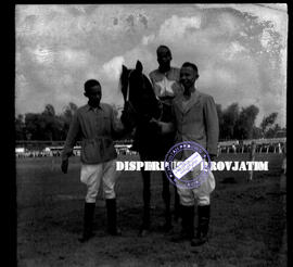 Dua orang joki tengah berfoto dengan memegang tali kendali kuda dengan seorang penunggang kuda da...